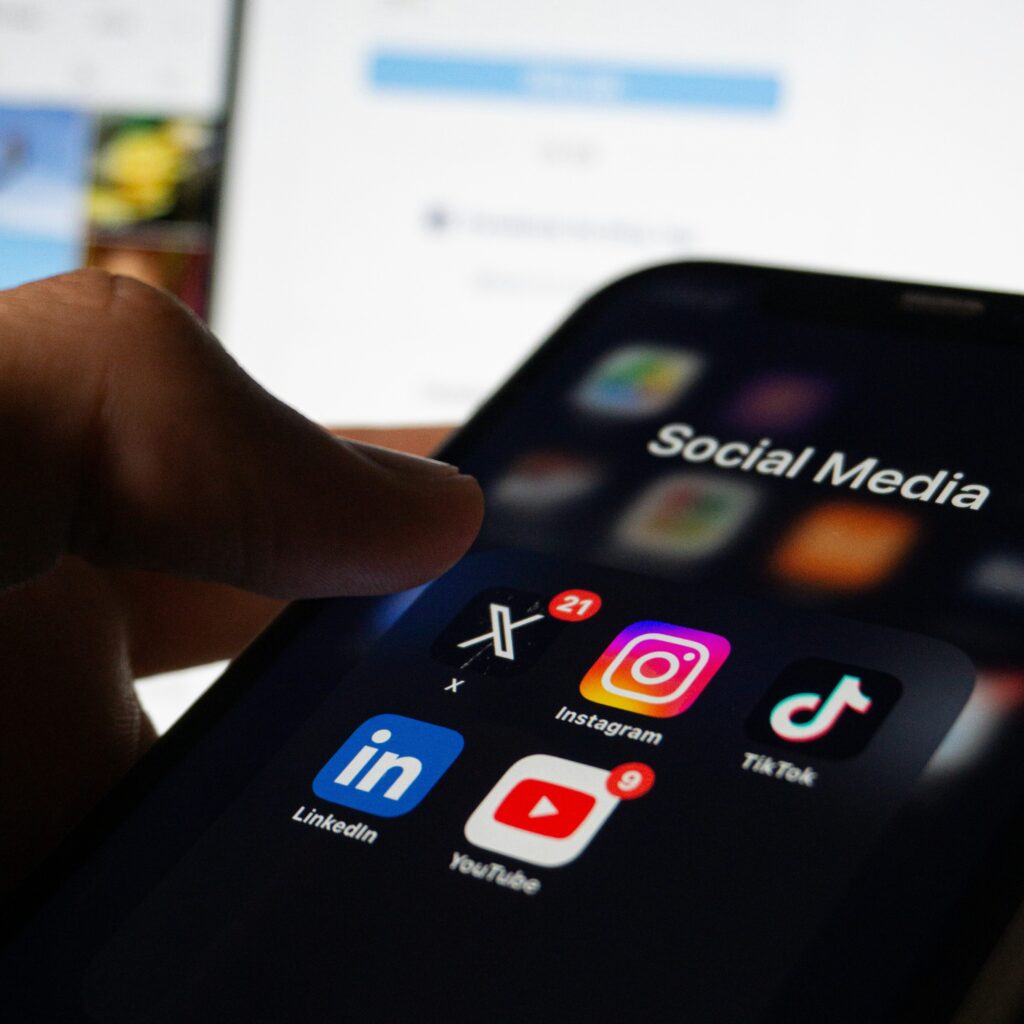 Smartphone screen showing social media app icons including Instagram, TikTok, LinkedIn, and YouTube